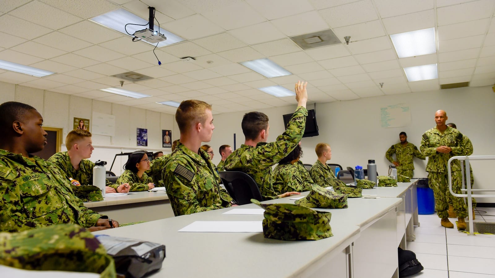 A U.S. Navy chief in uniform addresses a group of sailors seated in a bright classroom during an Information Warfare Training Command course at NAS Pensacola Corry Station