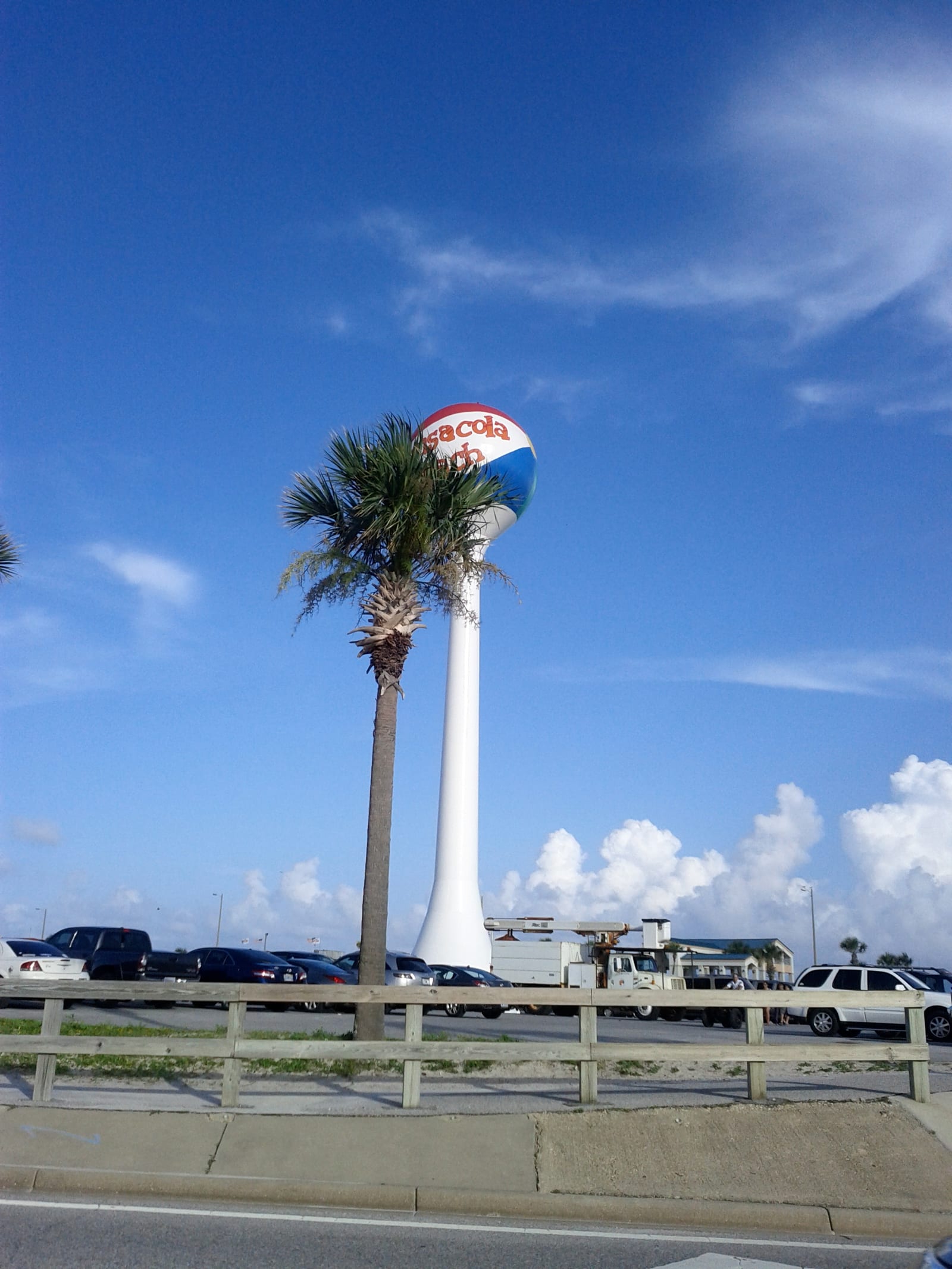 Pensacola Beach beach ball water tower against a blue sky with a palm tree