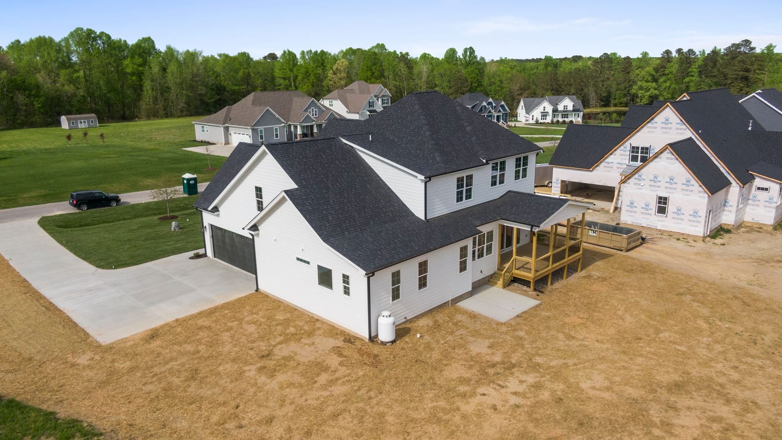 Aerial view of new-construction homes in a wooded suburban neighborhood