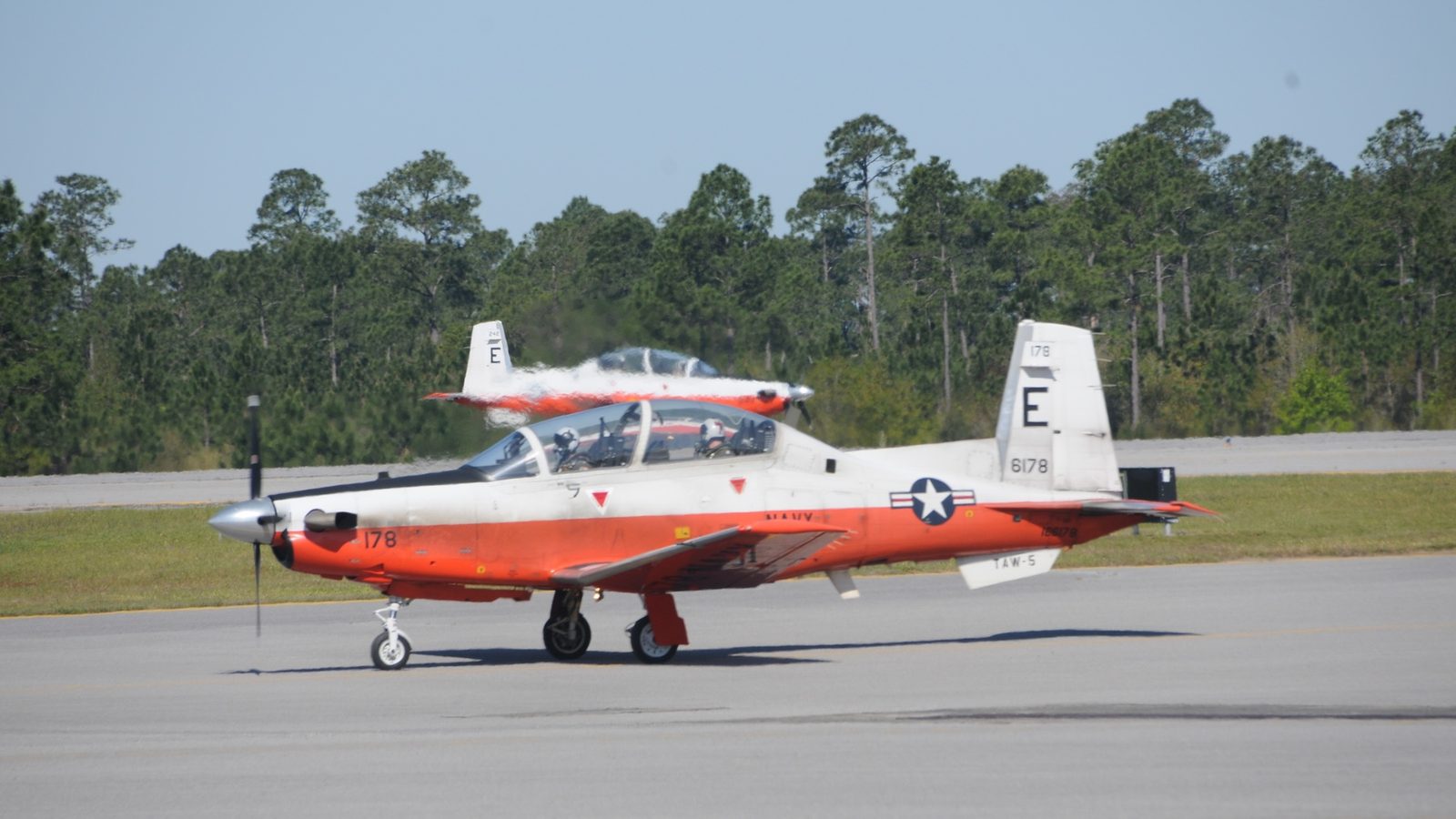 Two orange-and-white U.S. Navy T-6B Texan II trainers taxiing at NAS Whiting Field