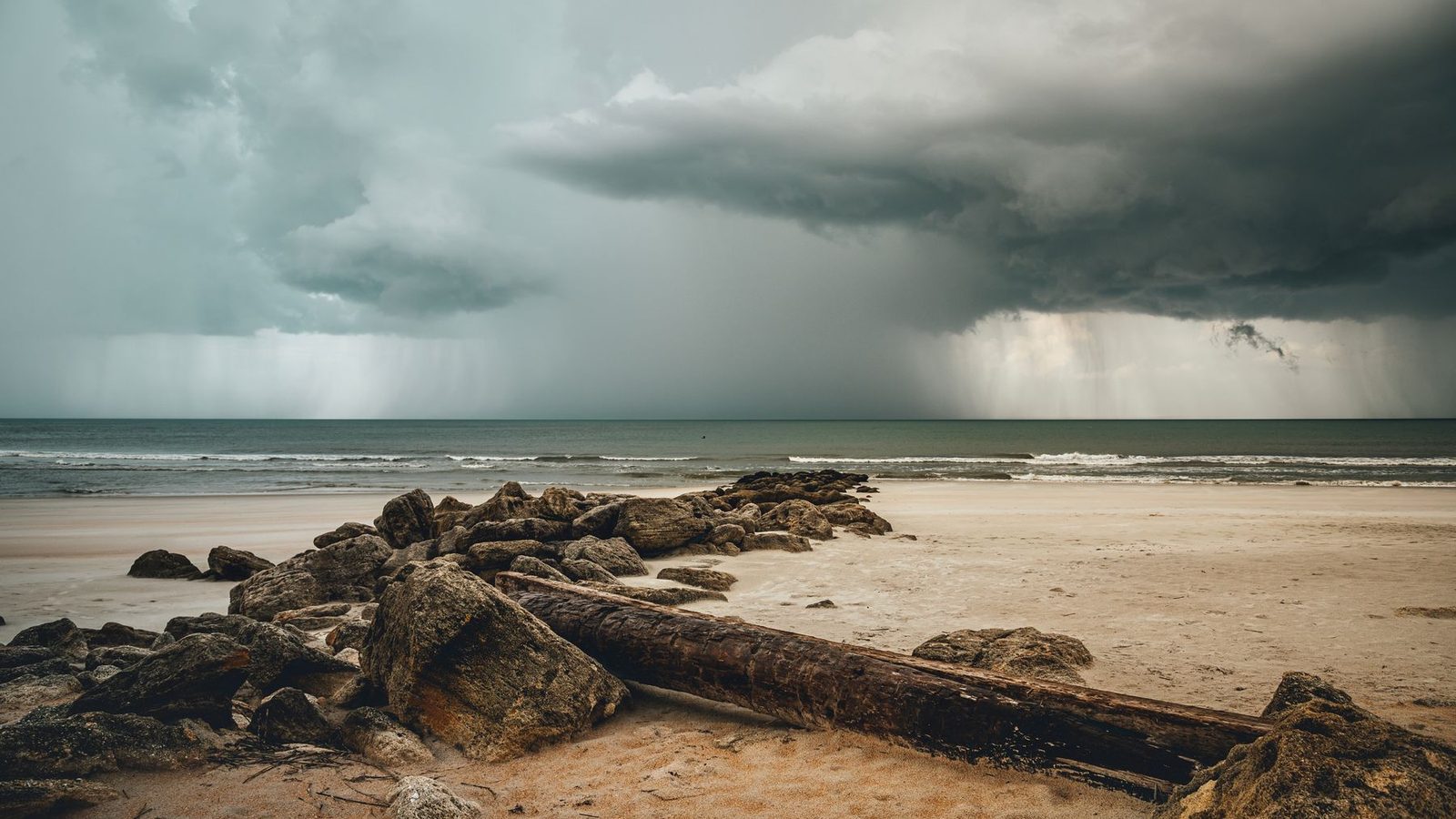A summer storm cell dropping rain over the Gulf of Mexico seen from the beach