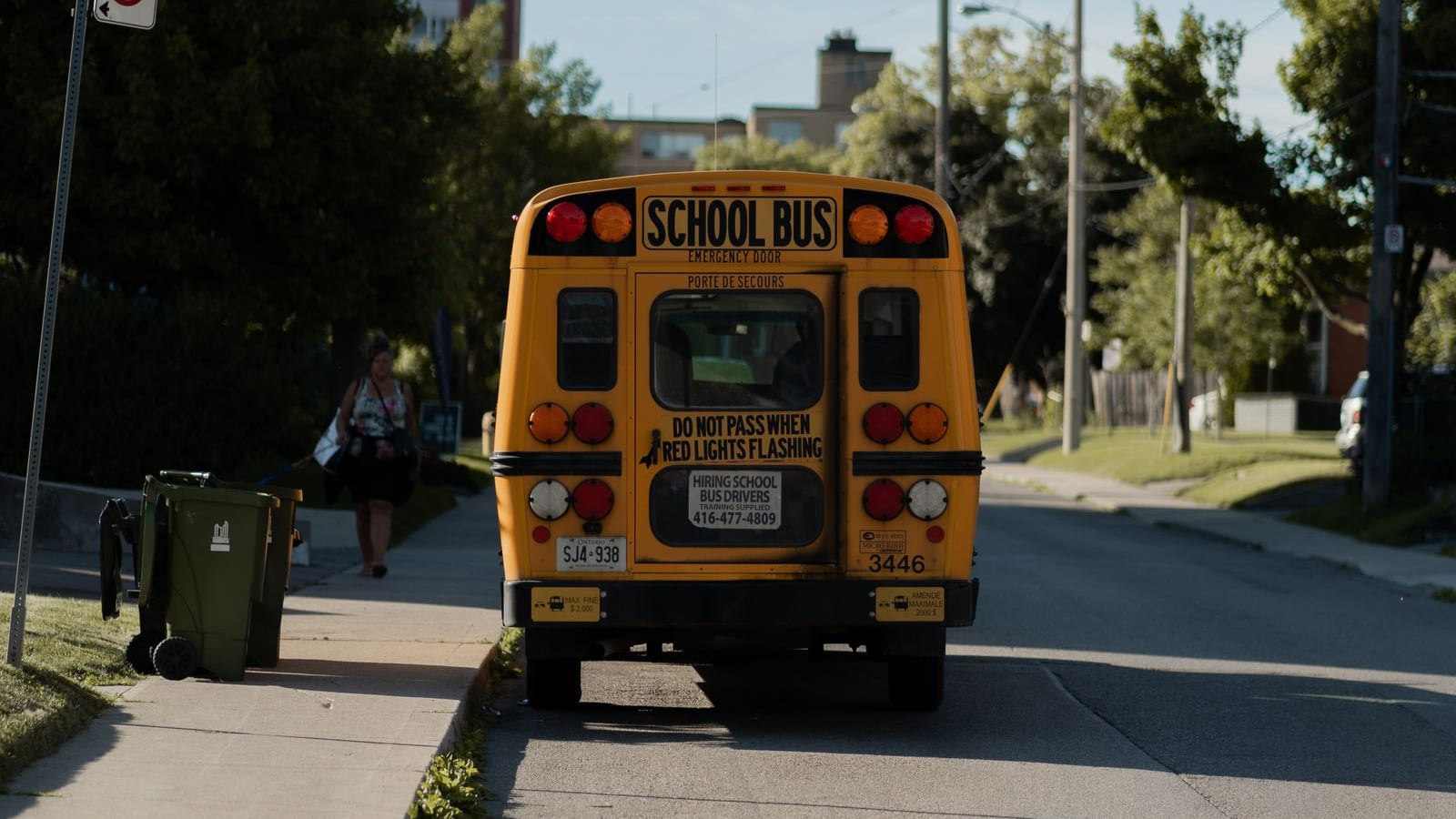 A classic bright yellow American school bus parked on a suburban street under a clear blue sky