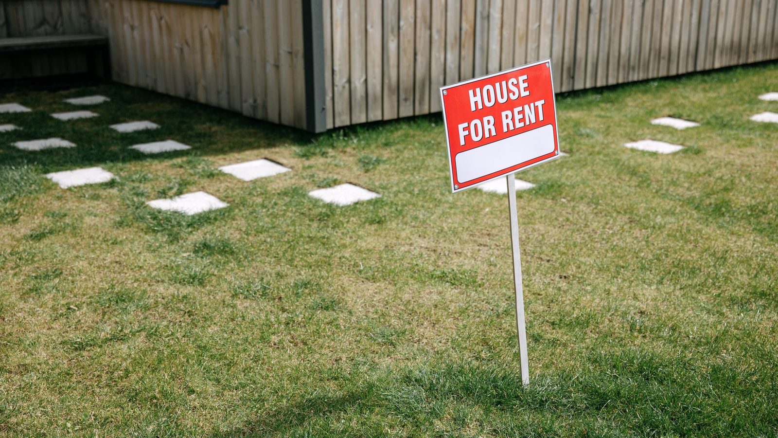 A house-for-rent sign staked in the front yard of a home